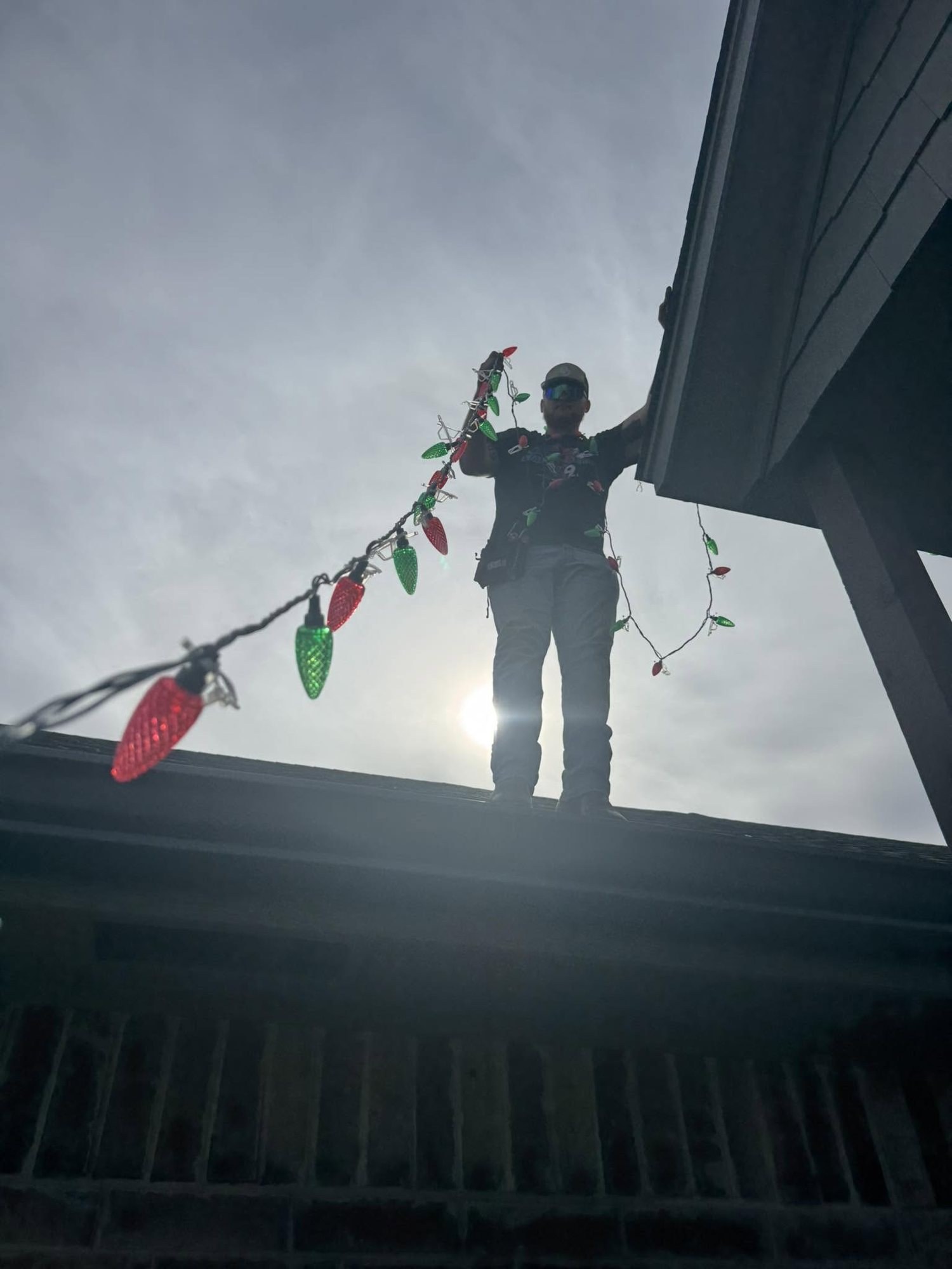 Kolby hanging C9 lights along a roofline